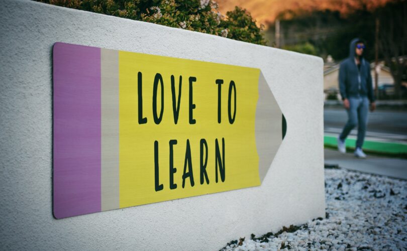 love to learn pencil signage on wall near walking man